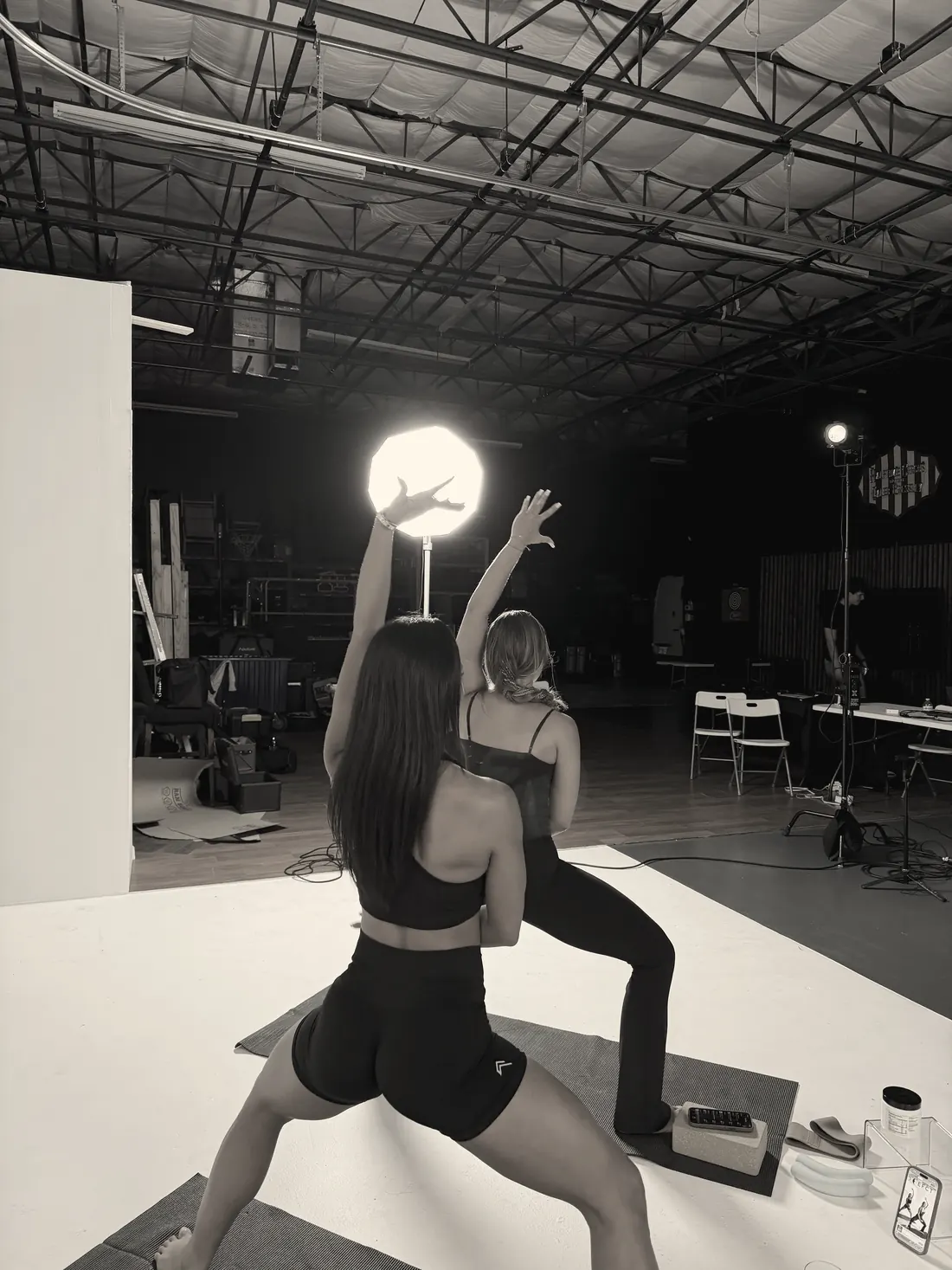 Two women holding a yoga pose in a studio